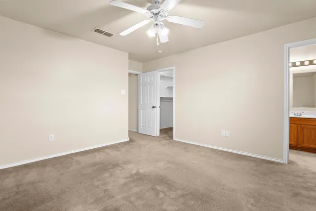 an empty room with chandelier fan and closet area