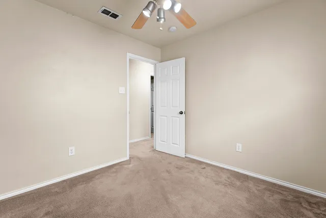 an empty room with a chandelier fan and closet