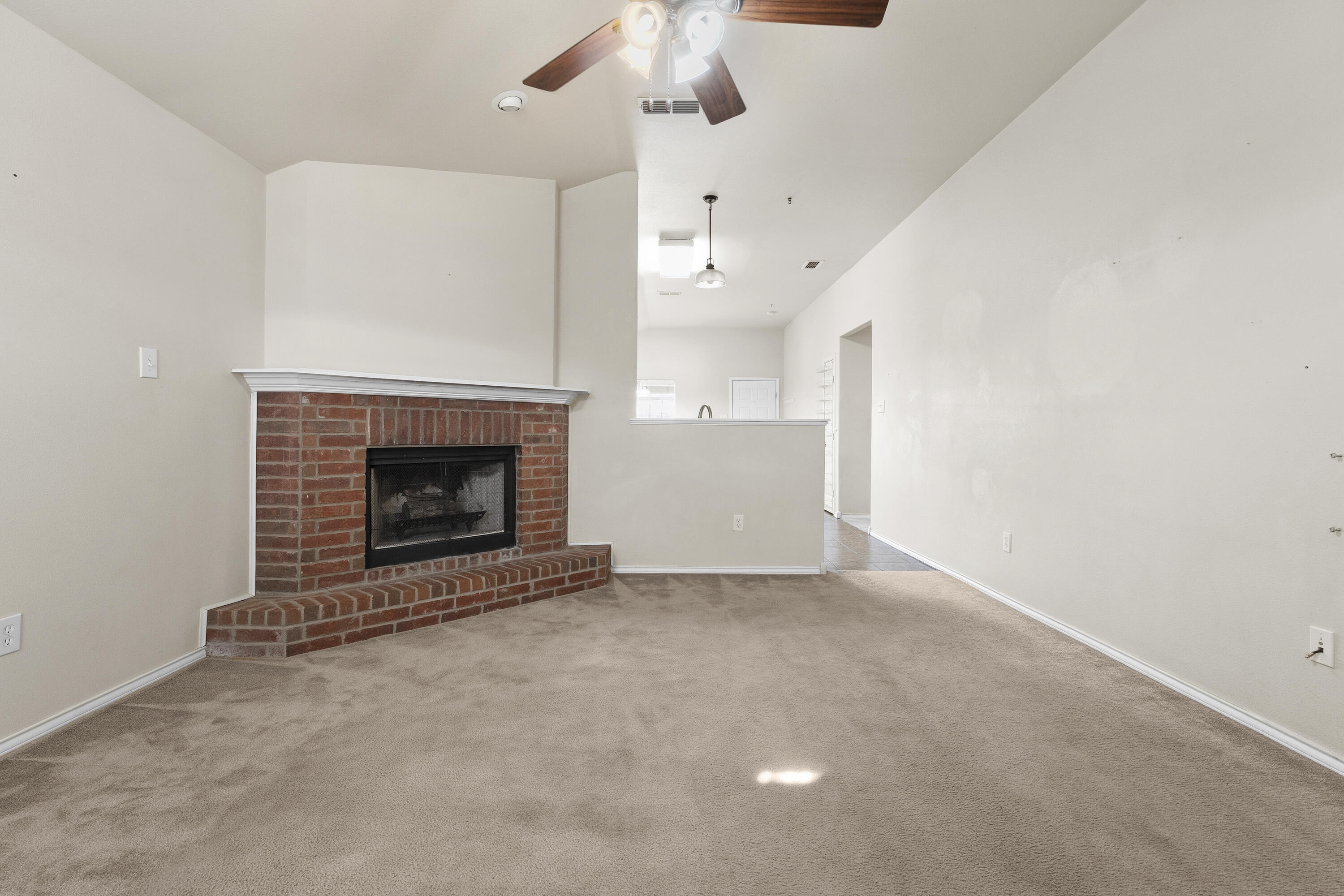 6522 93rd Street Lubbock, TX 79424 - Photo 4 of 22 an empty room with a fireplace and fan