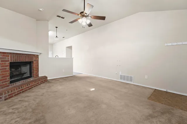 an empty room with chandelier fan and fireplace