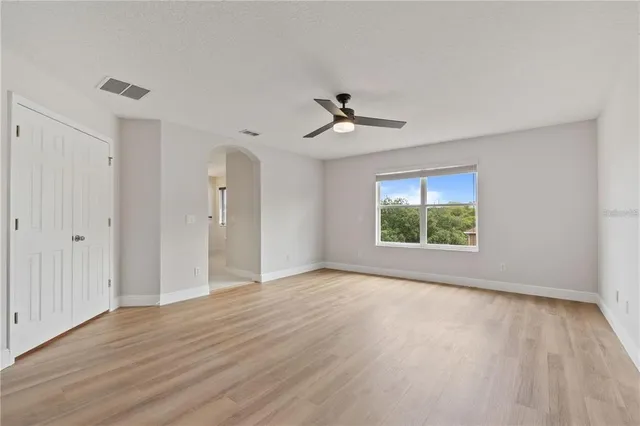 a view of an empty room with a window and wooden floor