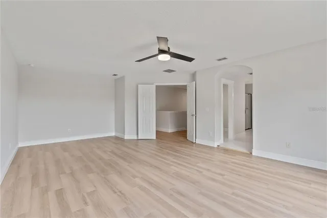 a view of an empty room with a ceiling fan window and a ceiling fan