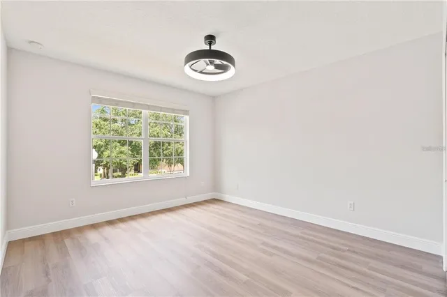 an empty room with wooden floor and windows