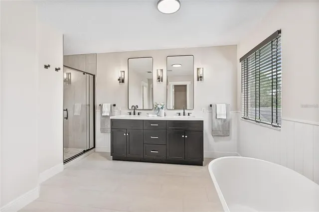 a spacious bathroom with a double vanity sink a mirror a bathtub and shower