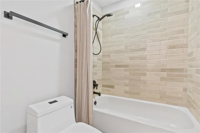 a bathroom with a granite countertop bathtub shower and toilet