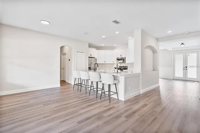 a kitchen with white cabinets stainless steel appliances with chair and table