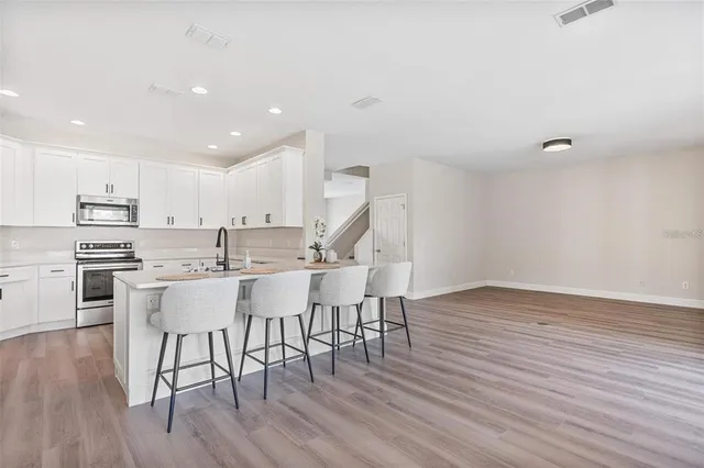 a kitchen with a wooden floor and chairs