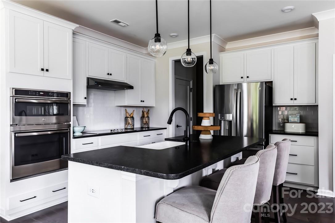 a kitchen with stainless steel appliances a stove a sink a refrigerator a center island and cabinets