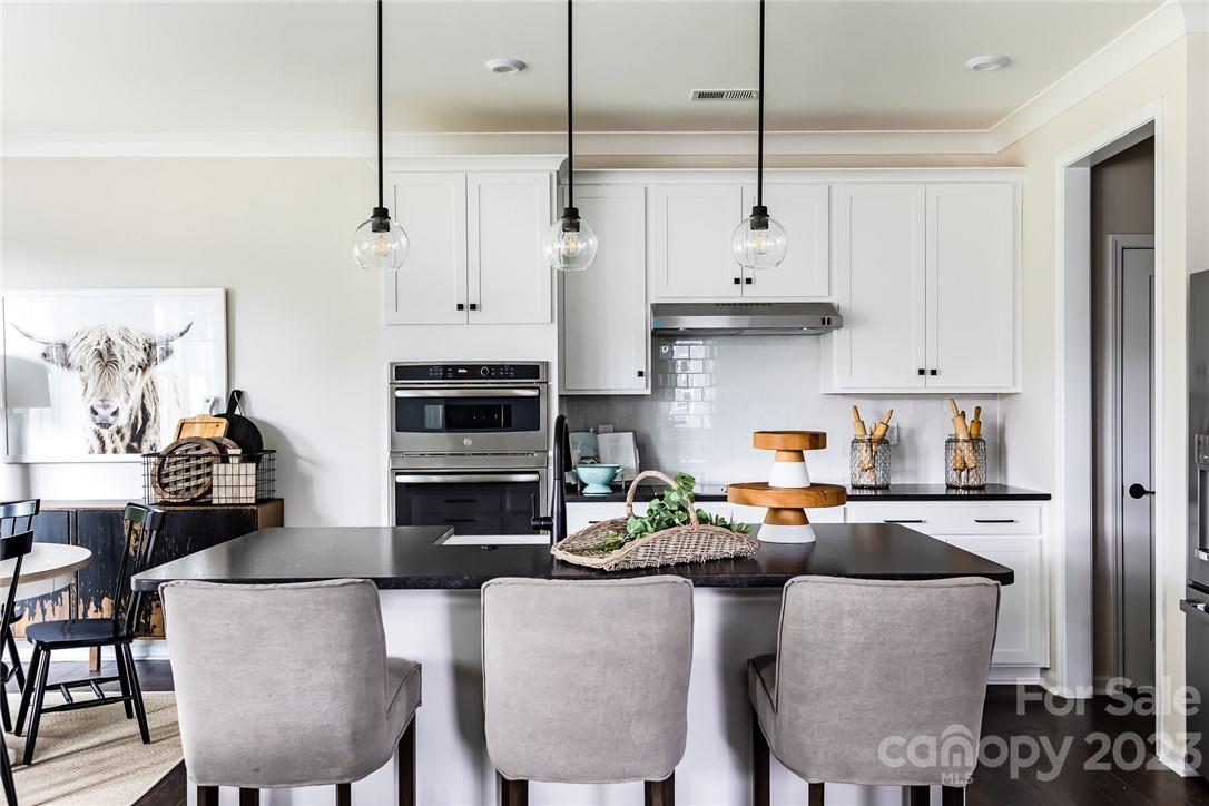 216 Brooks Springs Drive Fort Mill, SC 29708 - Photo 10 of 24 a kitchen with stainless steel appliances granite countertop a stove a refrigerator a kitchen island a dining table and chairs