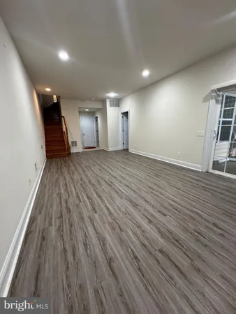 a view of an empty room with wooden floor and windows