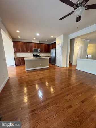 a view of a kitchen with kitchen island a sink wooden floor and a living room view