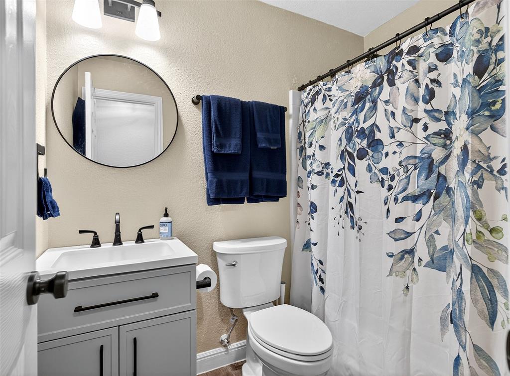1006 Oakchase Court Azle, TX 76020 - Photo 9 of 19 a bathroom with a toilet sink vanity and mirror