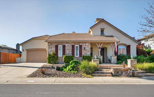 a front view of a house with a yard and potted plants