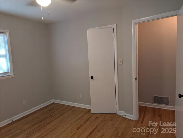 an empty room with wooden floor cabinet and windows