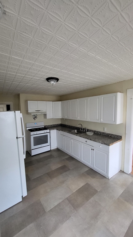 238 Hildreth Street, Unit 238 Lowell, MA 01850 - Photo 4 of 16 a large kitchen with a stove a sink and a refrigerator