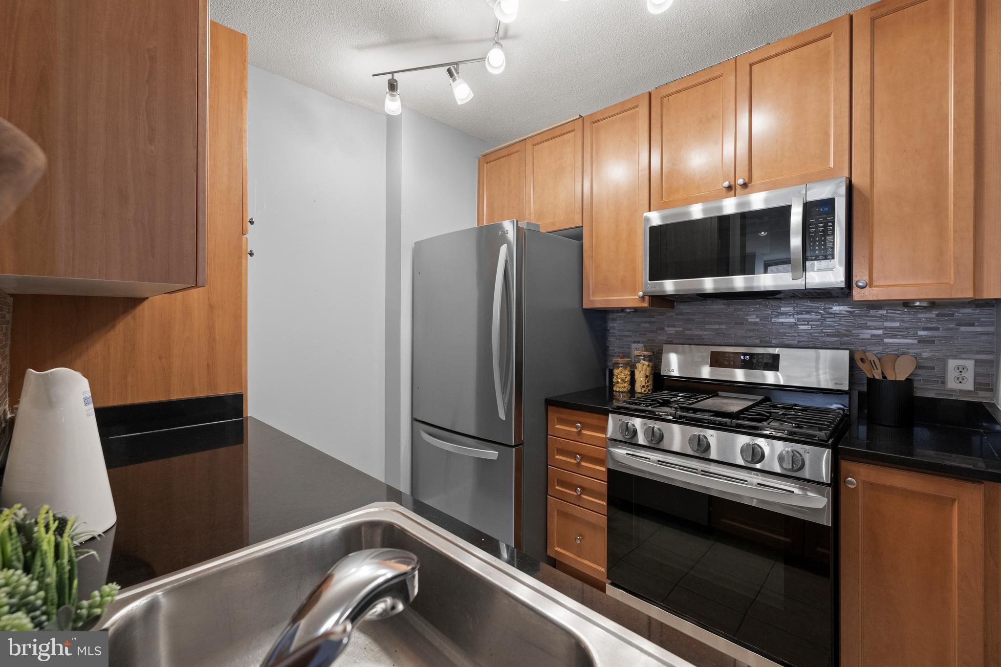 851 North Glebe Road, Unit 1508 Arlington, VA 22203 - Photo 7 of 41 a kitchen with granite countertop a refrigerator and a sink