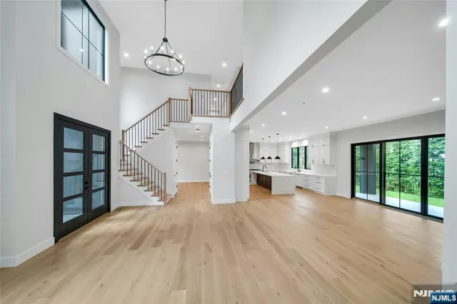 a view of an empty room with wooden floor kitchen view and a window