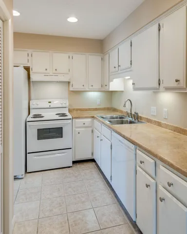 a kitchen with granite countertop white cabinets and white appliances