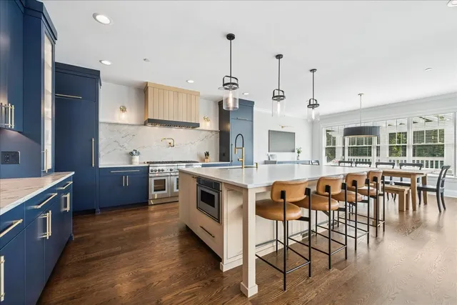 a kitchen with stainless steel appliances granite countertop wooden floors and white cabinets