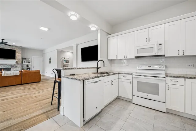 a kitchen with granite countertop a sink stainless steel appliances and white cabinets
