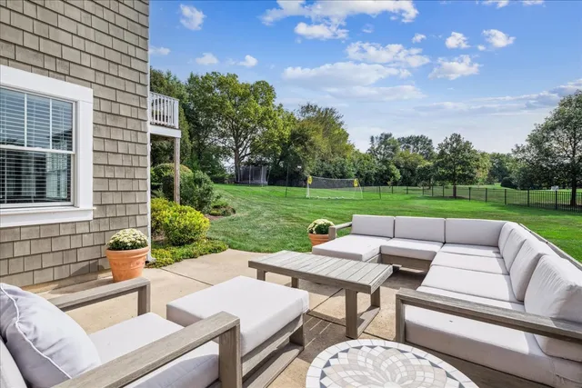a view of a patio with couches and table and chairs with wooden fence and plants