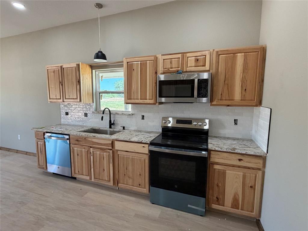 1040 Rays Way Weatherford, TX 76085 - Photo 9 of 23 Modern kitchen featuring light wood cabinetry, stone countertops, and stainless steel appliances