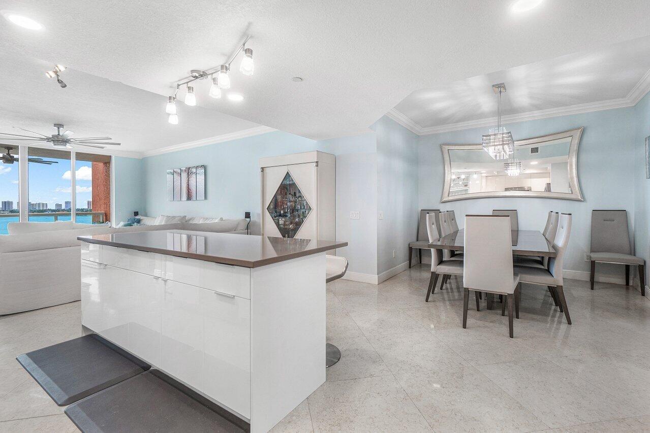 2650 Lake Shore Drive, Unit 701 Riviera Beach, FL 33404 - Photo 13 of 64 a kitchen with kitchen island a dining table chairs cabinets and stainless steel appliances