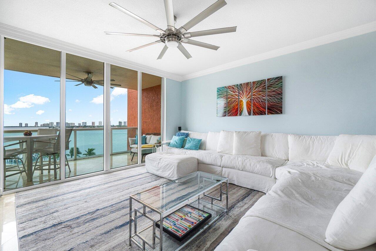 2650 Lake Shore Drive, Unit 701 Riviera Beach, FL 33404 - Photo 3 of 64 a living room with furniture a flat screen tv and a floor to ceiling window