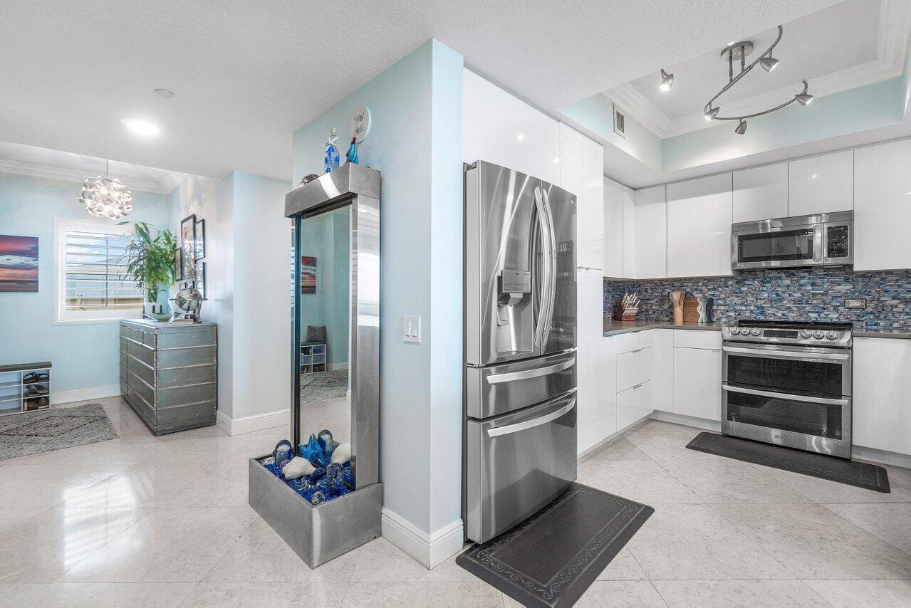 2650 Lake Shore Drive, Unit 701 Riviera Beach, FL 33404 - Photo 7 of 64 a kitchen with stainless steel appliances kitchen island granite countertop a refrigerator and a stove top oven