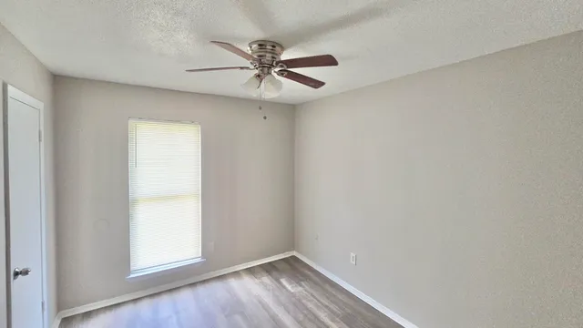 an empty room with wooden floor closet and fan