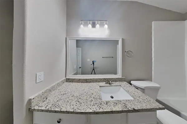 a bathroom with a granite countertop sink and a mirror