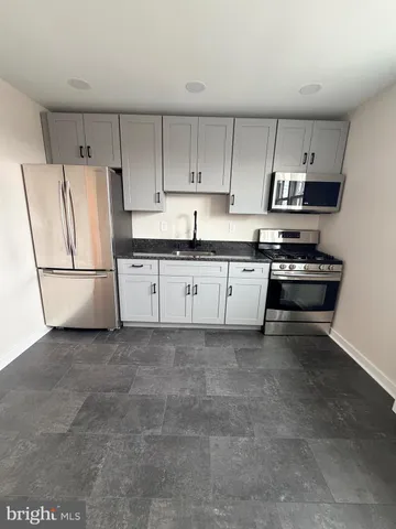 a kitchen with granite countertop a refrigerator sink and white cabinets
