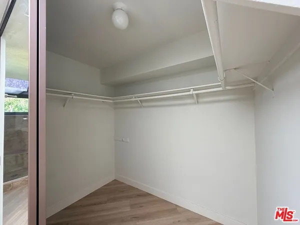 a view of an empty walk in closet with wooden floor