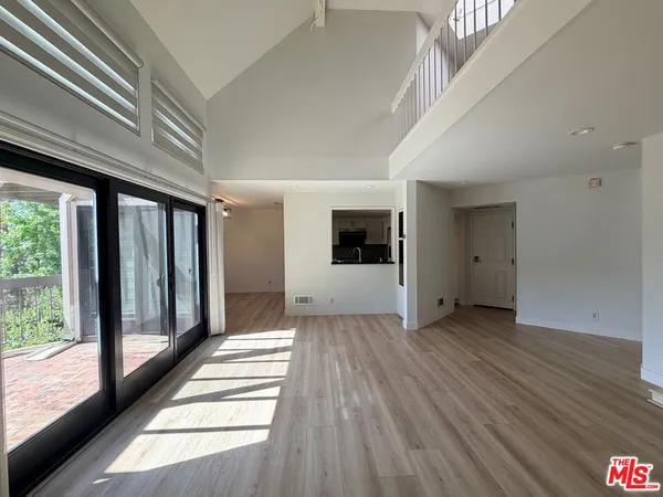 a view of a hallway with wooden floor and a kitchen