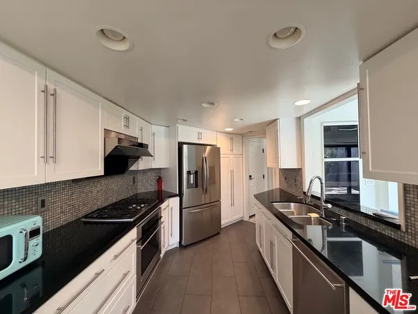 a kitchen with stainless steel appliances granite countertop a sink stove and refrigerator