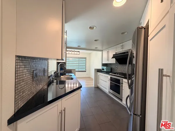 a kitchen with kitchen island granite countertop a sink stainless steel appliances and cabinets