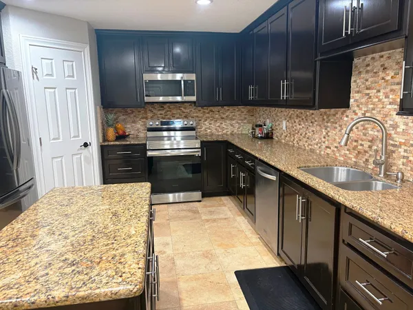 a kitchen with stainless steel appliances granite countertop a stove refrigerator sink and cabinets