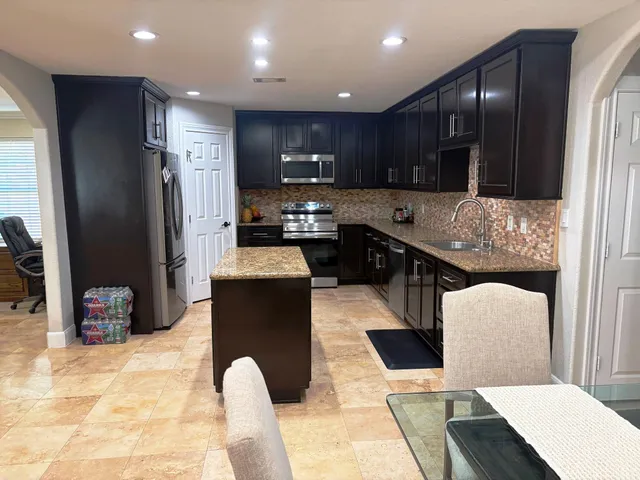 a kitchen with stainless steel appliances kitchen island granite countertop a refrigerator a stove a sink and a microwave