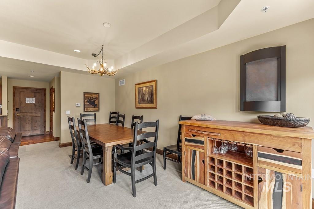 616 North 3rd Street, Unit 304 McCall, ID 83638 - Photo 14 of 38 Dining room with light colored carpet, a chandelier, and a raised ceiling