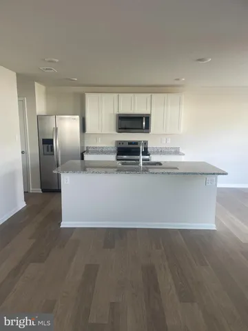 a large kitchen with kitchen island a large counter top space and stainless steel appliances