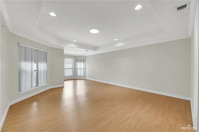 a view of empty room with wooden floor and fan