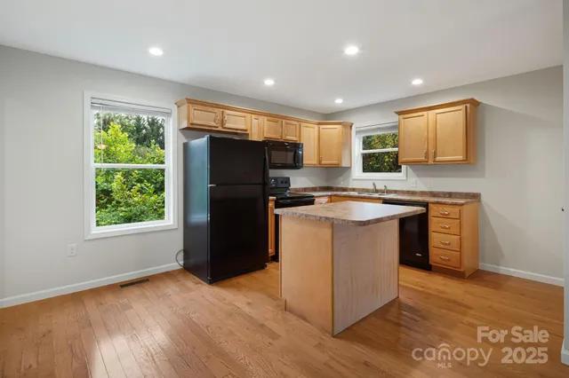 a kitchen with stainless steel appliances granite countertop a stove a refrigerator a sink a microwave and island with wooden floor