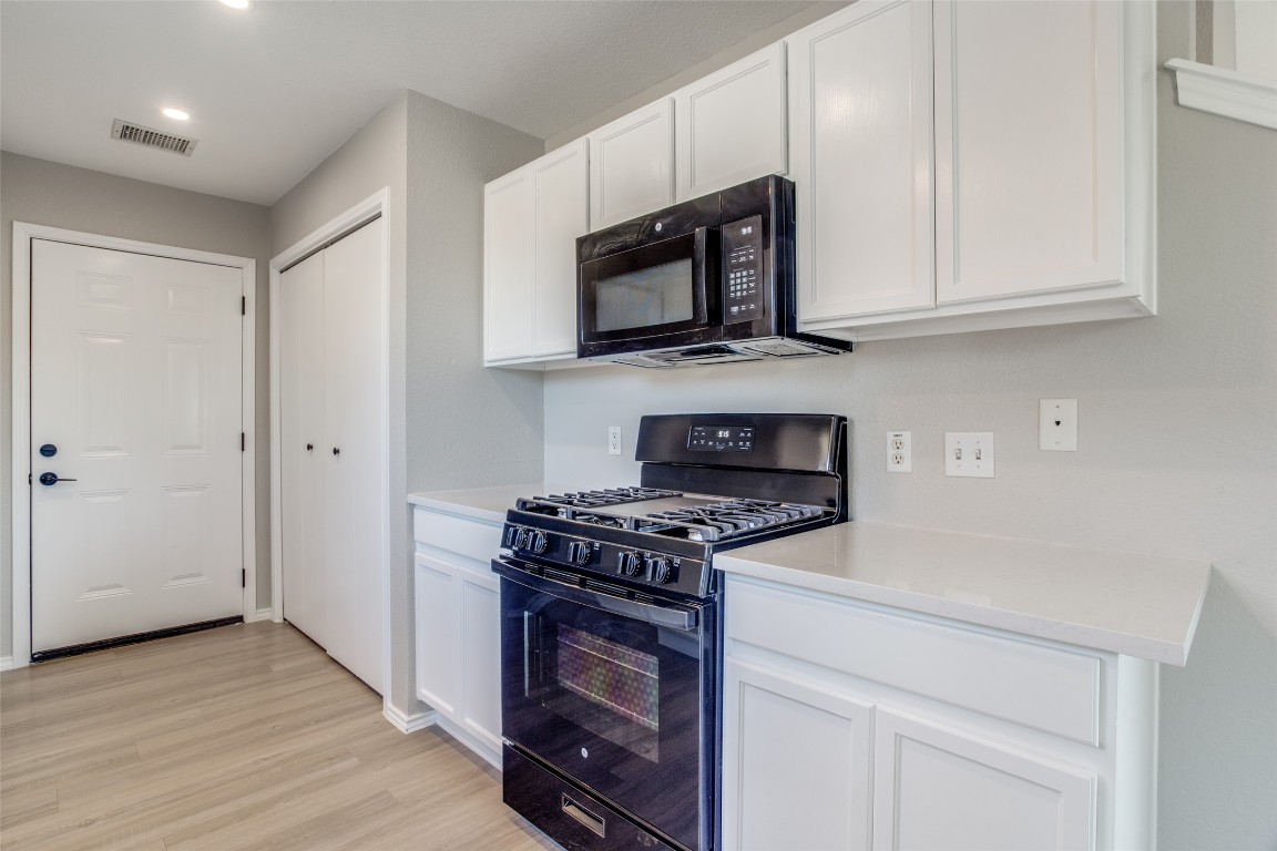13145 Briarcreek Loop Manor, TX 78653 - Photo 12 of 25 a kitchen with stainless steel appliances granite countertop white cabinets and a stove top oven