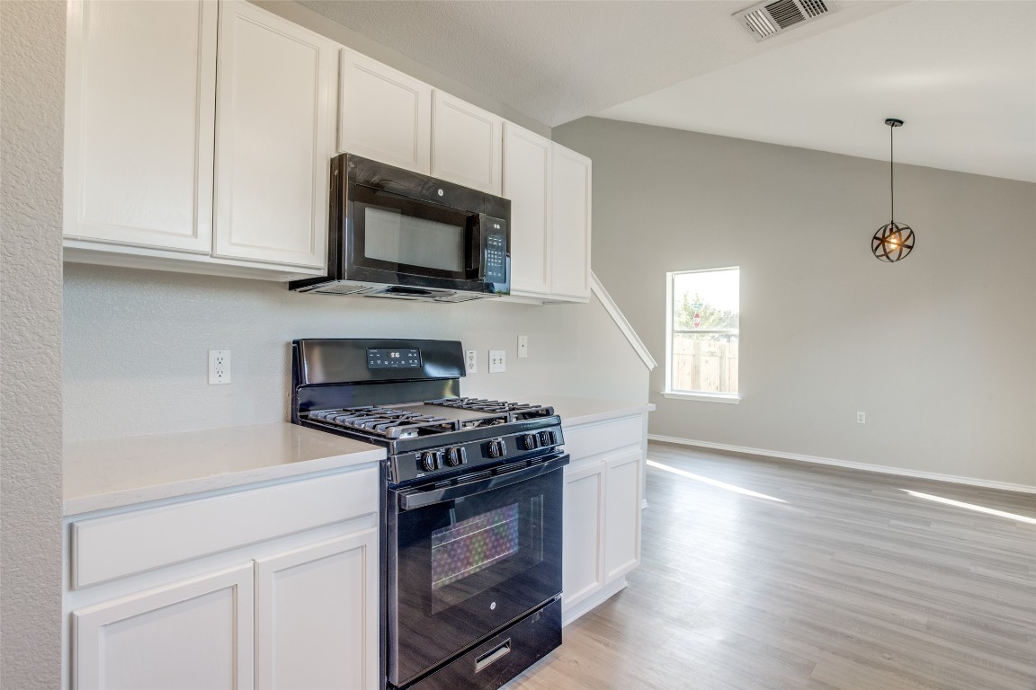 13145 Briarcreek Loop Manor, TX 78653 - Photo 13 of 25 a kitchen with stainless steel appliances a stove a microwave and cabinets