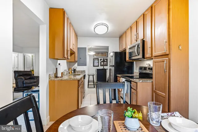 a kitchen with stainless steel appliances granite countertop a refrigerator a stove and a dining table with wooden floor