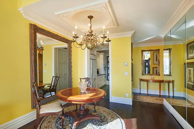 a view of a dining room with furniture a chandelier and large windows