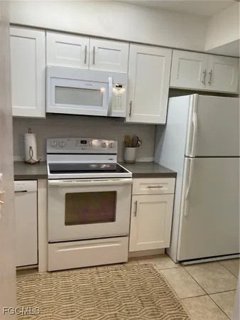 a kitchen with white cabinets and white appliances