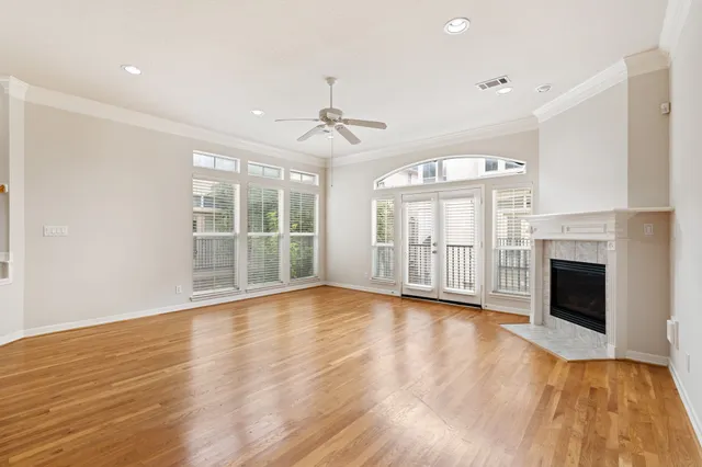 a view of an empty room with wooden floor fireplace and a window