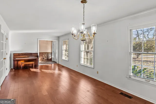 a view of a room with wooden floor chandelier and windows