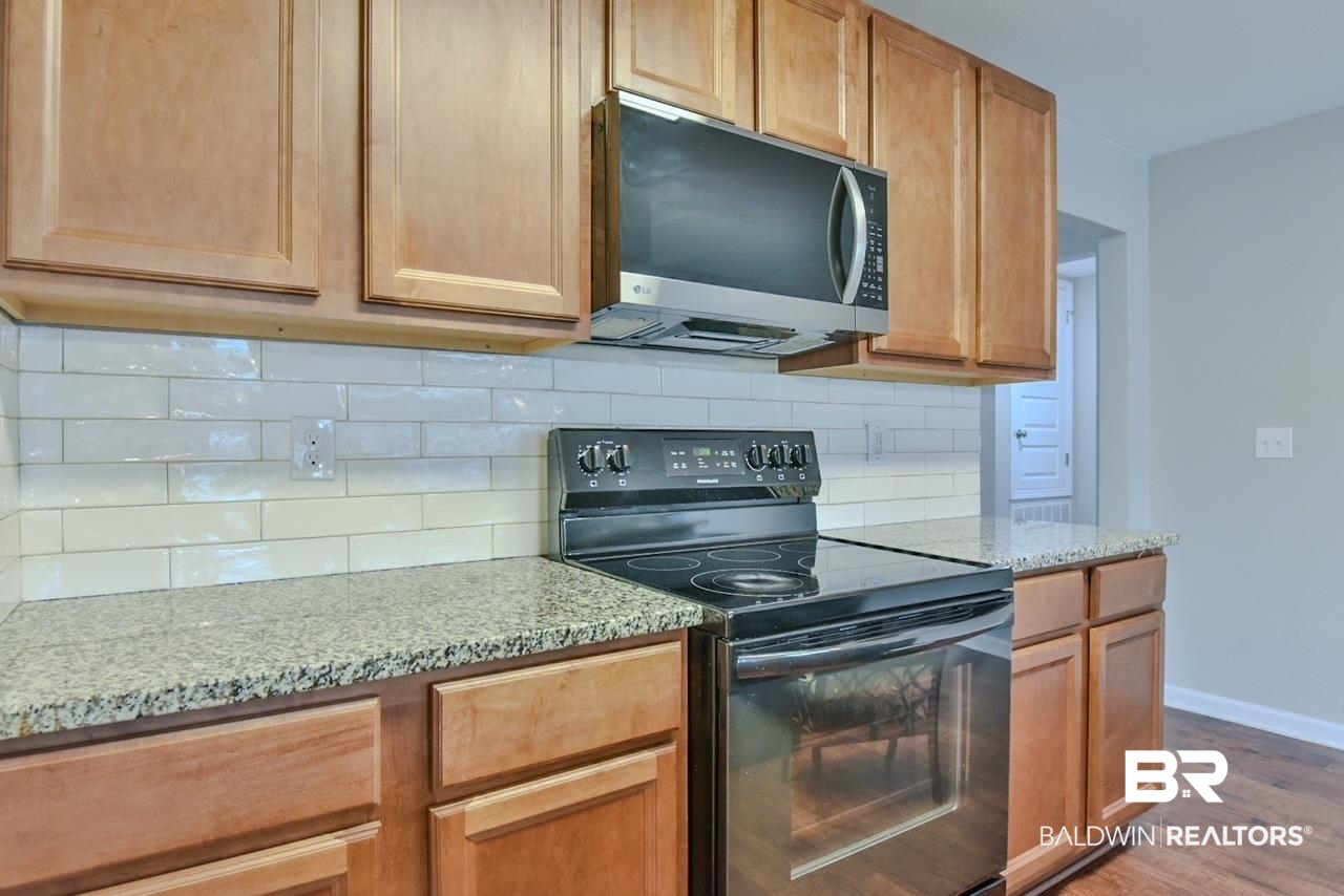 17430 Harding Drive Foley, AL 36535 - Photo 8 of 37 Kitchen featuring light wood finished floors, light stone counters, black range with electric stovetop, and baseboards